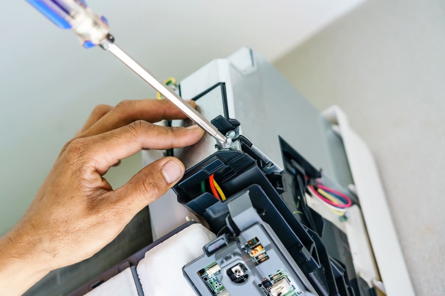 A screwdriver fastening a screw onto an air conditioning unit