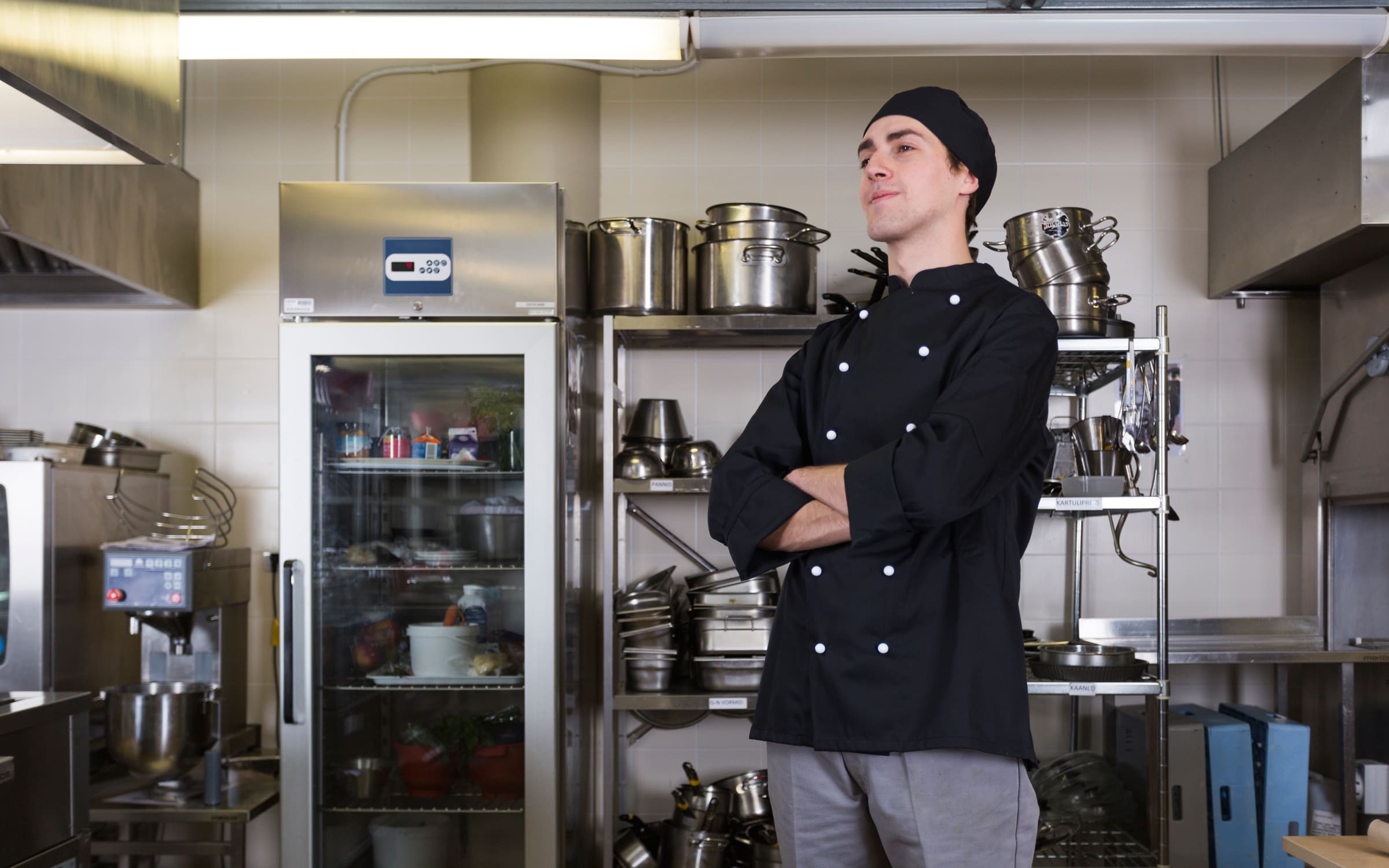 commercial stainless‑steel restaurant kitchen with multiple refrigerators, prep counters, and industrial cooking equipment